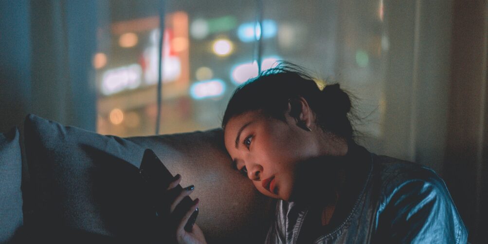 Younger worker looking at her phone at night